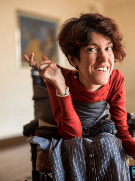Disabled woman in wheelchair smiling and looking past camera